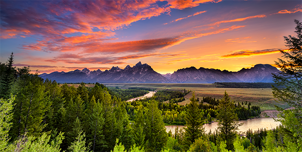 A colorful sunset over the mountains and valley with a winding river in Wyoming.
